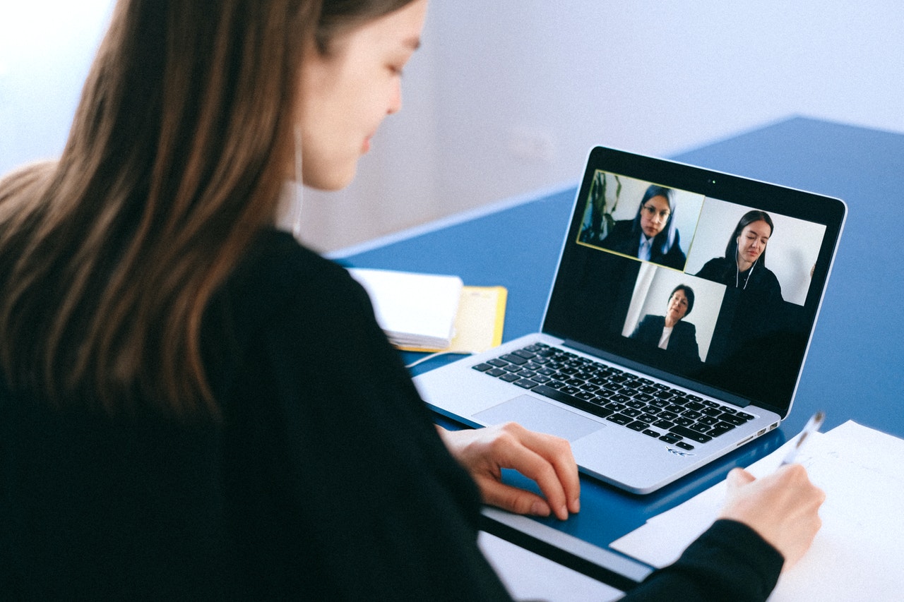 woman on video call sat in front of laptop with 3 other video call participants on screen