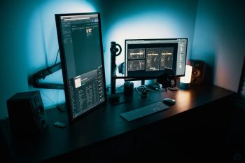 vertical pc screen and horizontal pc screen on desk in dimly lit room