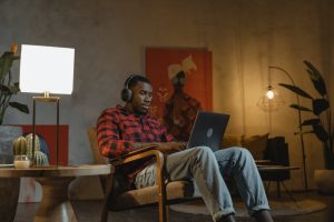 man-in-big-chair-working-on-laptop-headphones-on