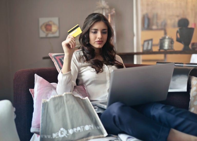 woman sitting in chair with laptop and holding a credit card