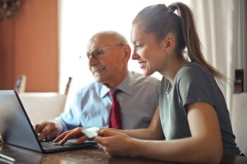 woman and man sat looking at laptop and smiling