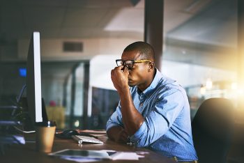 man sat at laptop with head in hands