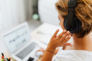 woman sat at laptop with headphones on