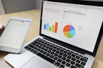 laptop and tablet on table showing survey charts